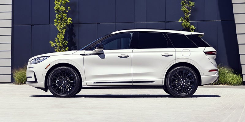 A 2024 white Lincoln Corsair with black-tinted windows and rims is parked beside a building in daylight near Elizabethtown, KY.