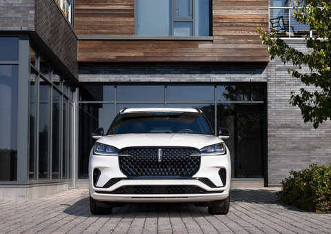 A white 2025 Lincoln Aviator® SUV is shown parked outside a modern building with gray brick and wood accents. | Don Franklin Lincoln Elizabethtown in Elizabethtown KY