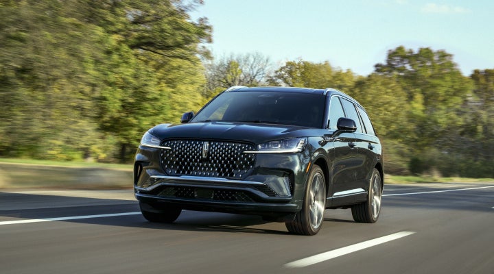 A 2026 Lincoln Black Label™ Aviator® SUV is being driven down a road lined with trees. | Don Franklin Lincoln Elizabethtown in Elizabethtown KY