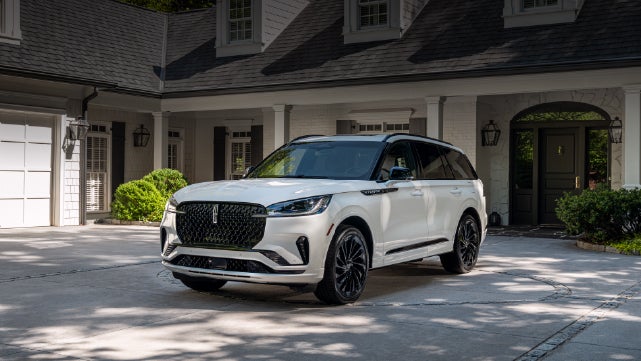 A white 2026 Lincoln Aviator® SUV is parked in the driveway of a luxury home. | Don Franklin Lincoln Elizabethtown in Elizabethtown KY