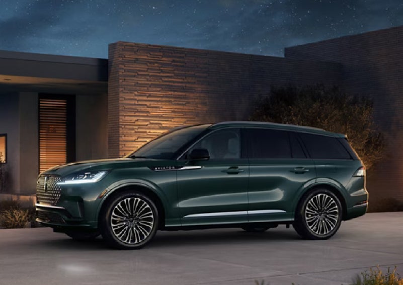 A green 2027 Lincoln Aviator® SUV is parked outside a contemporary home. | Don Franklin Lincoln Elizabethtown in Elizabethtown KY