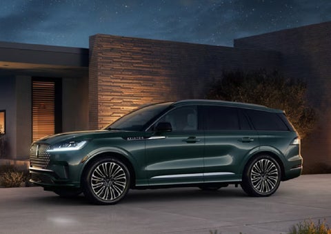 A green 2027 Lincoln Aviator® SUV is parked outside a contemporary home. | Don Franklin Lincoln Elizabethtown in Elizabethtown KY