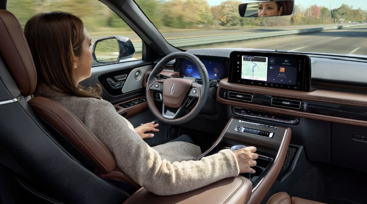 A 2027 Lincoln Aviator® SUV is being driven hands-free on a highway lined with trees. | Don Franklin Lincoln Elizabethtown in Elizabethtown KY