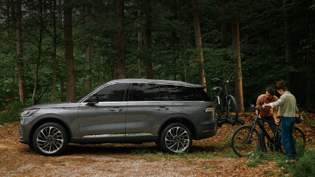 A father and son load e-bikes on a bike rack attached to a 2027 Lincoln Aviator® SUV. | Don Franklin Lincoln Elizabethtown in Elizabethtown KY