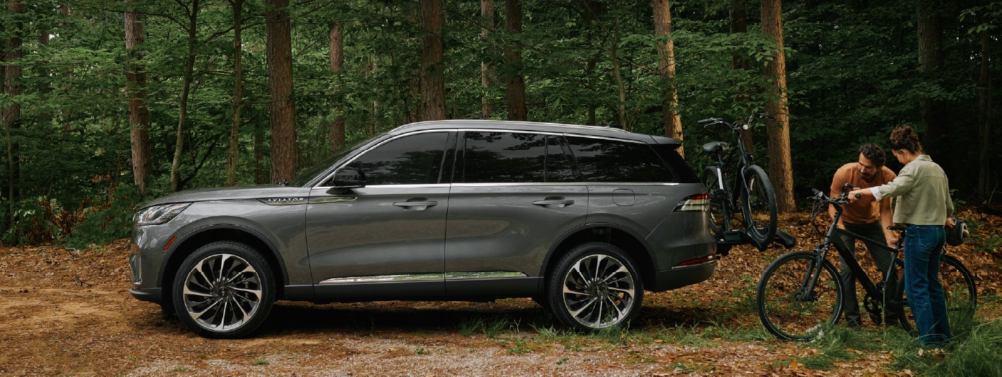 A father and son load e-bikes on a bike rack attached to a 2027 Lincoln Aviator® SUV. | Don Franklin Lincoln Elizabethtown in Elizabethtown KY